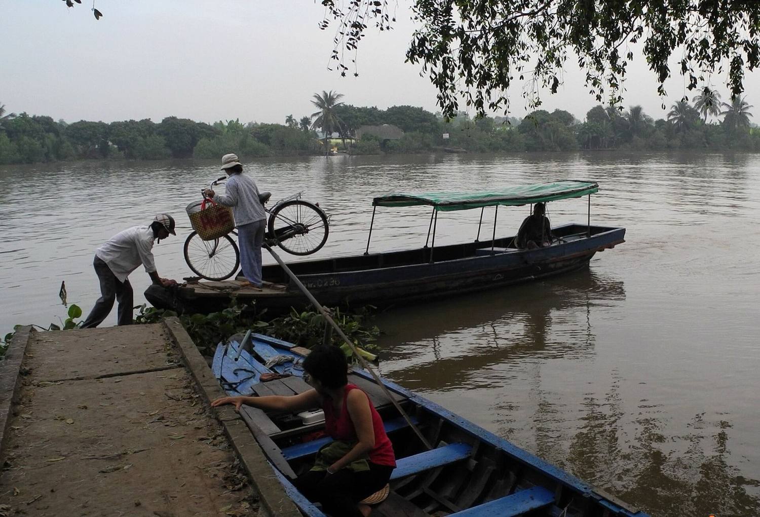 Penunggang basikal turun dari feri sungai di jalan ban Delta Mekong