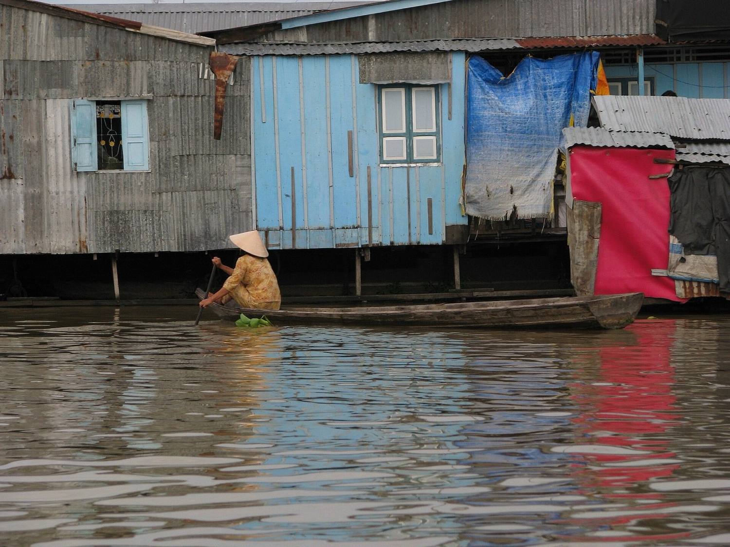 Bot kayu bergerak dalam kabus pagi di sebatang sungai Delta Mekong