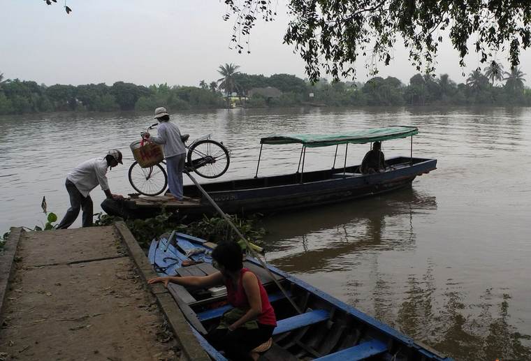 Penunggang basikal turun dari feri sungai di Delta Mekong